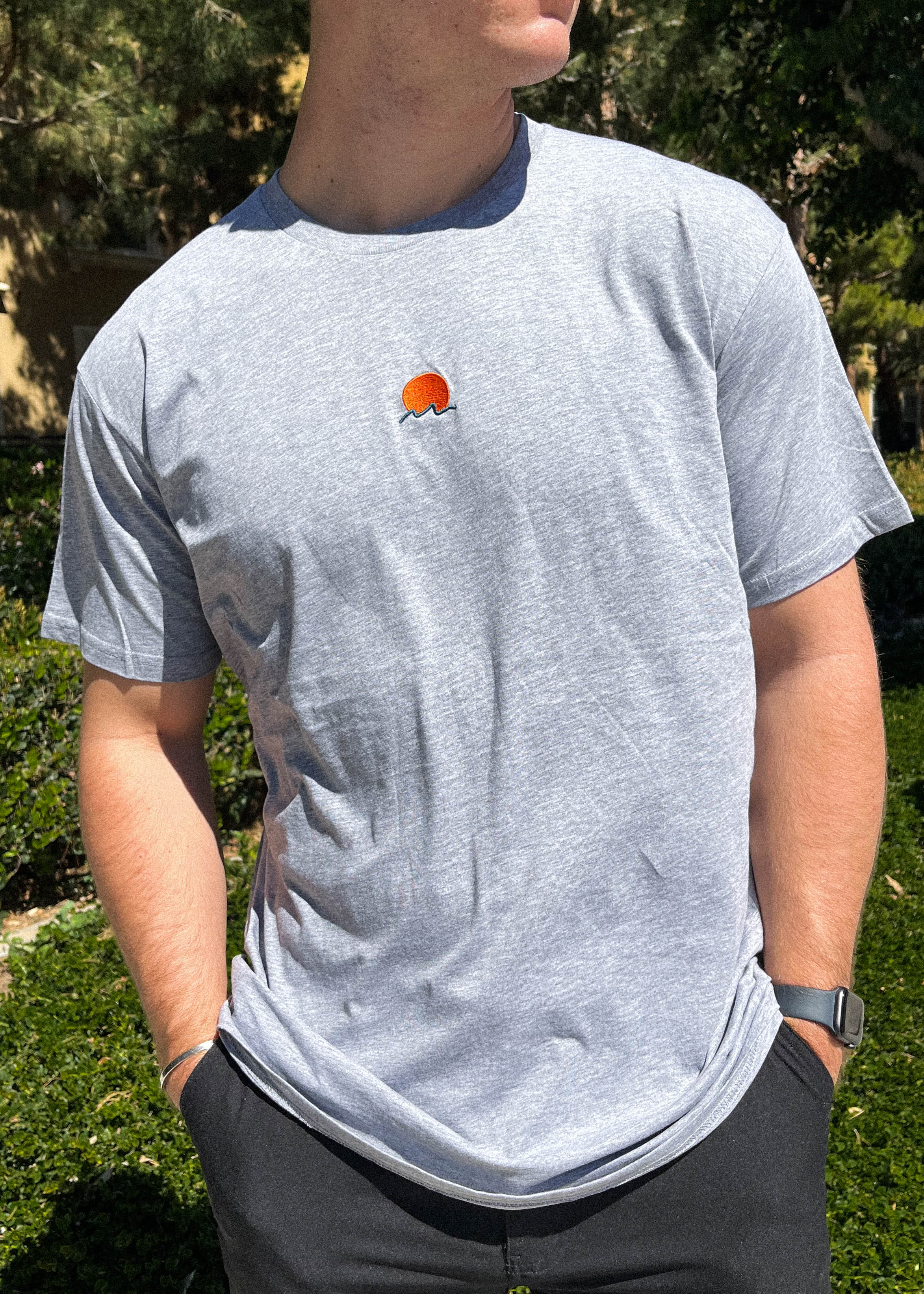 Rooted Swim Sunset Embroidered Tee Shirt in Heather Gray. Includes red sun and dark green wave design.
