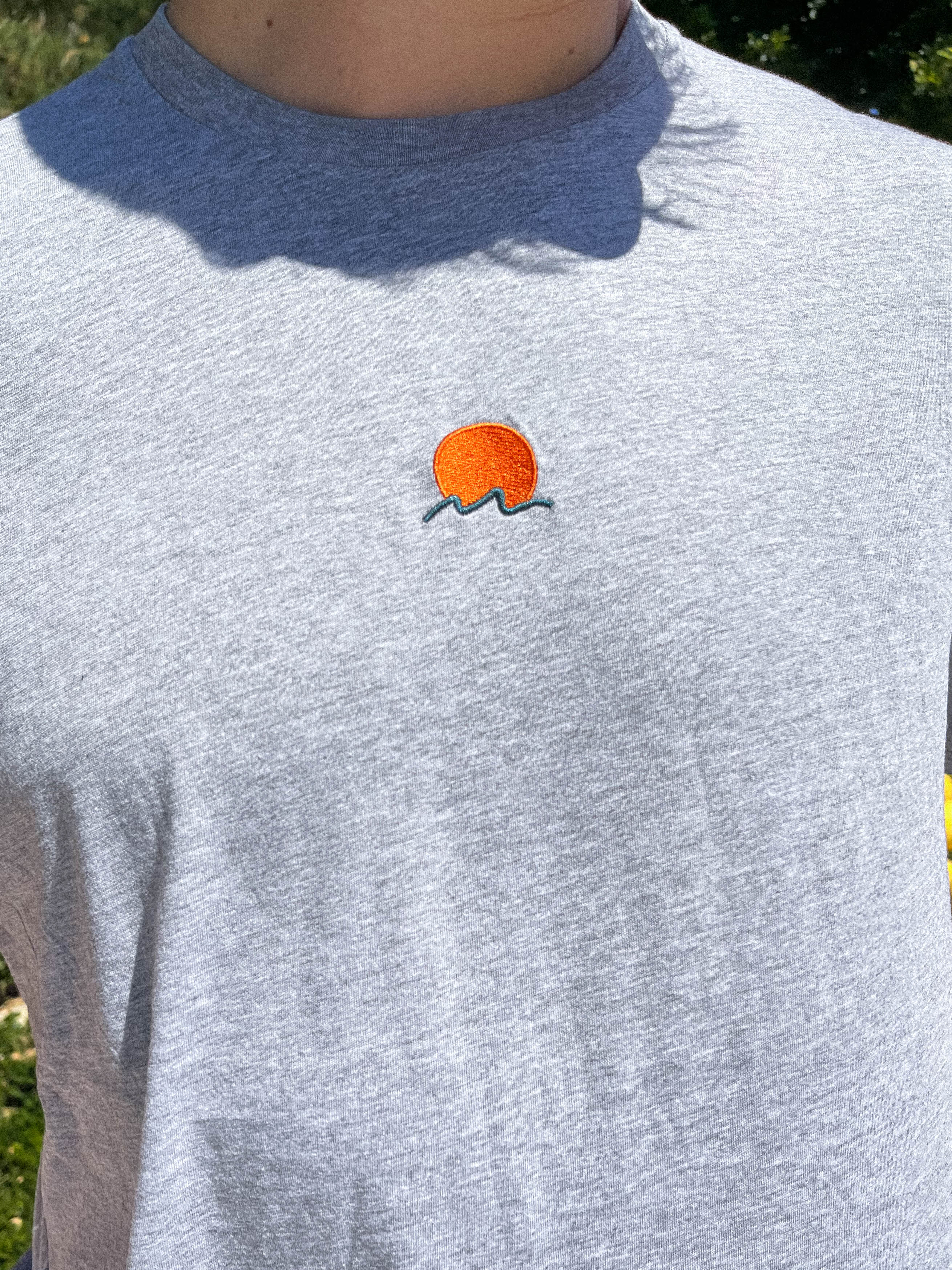 Rooted Swim Sunset Embroidered Tee Shirt in Heather Gray. Includes red sun and dark green wave design.