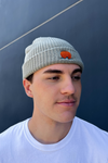 person wears classic cuffed knit fisherman beanie featuring embroidered Rooted Swim sunset logo in a soft green gray color. high quality knit beanie