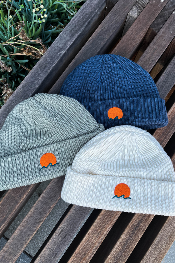 Classic cuffed knit fisherman beanies featuring embroidered Rooted Swim sunset logo in a blue gray color, soft seashell white and gray green color. high quality knit beanies